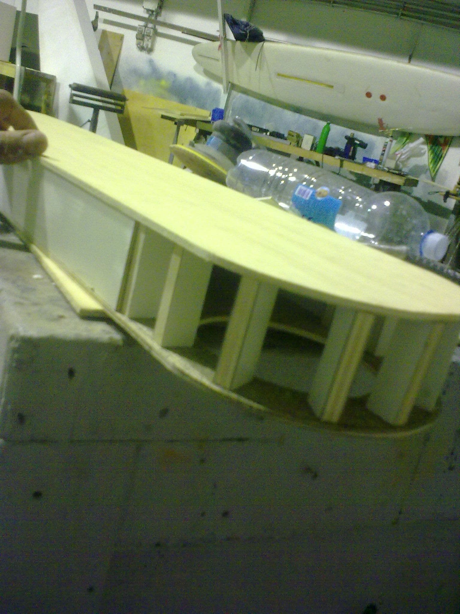 Dettaglio in primo piano della lavorazione artigianale in legno e compensato di un elemento curvo del camminatore.