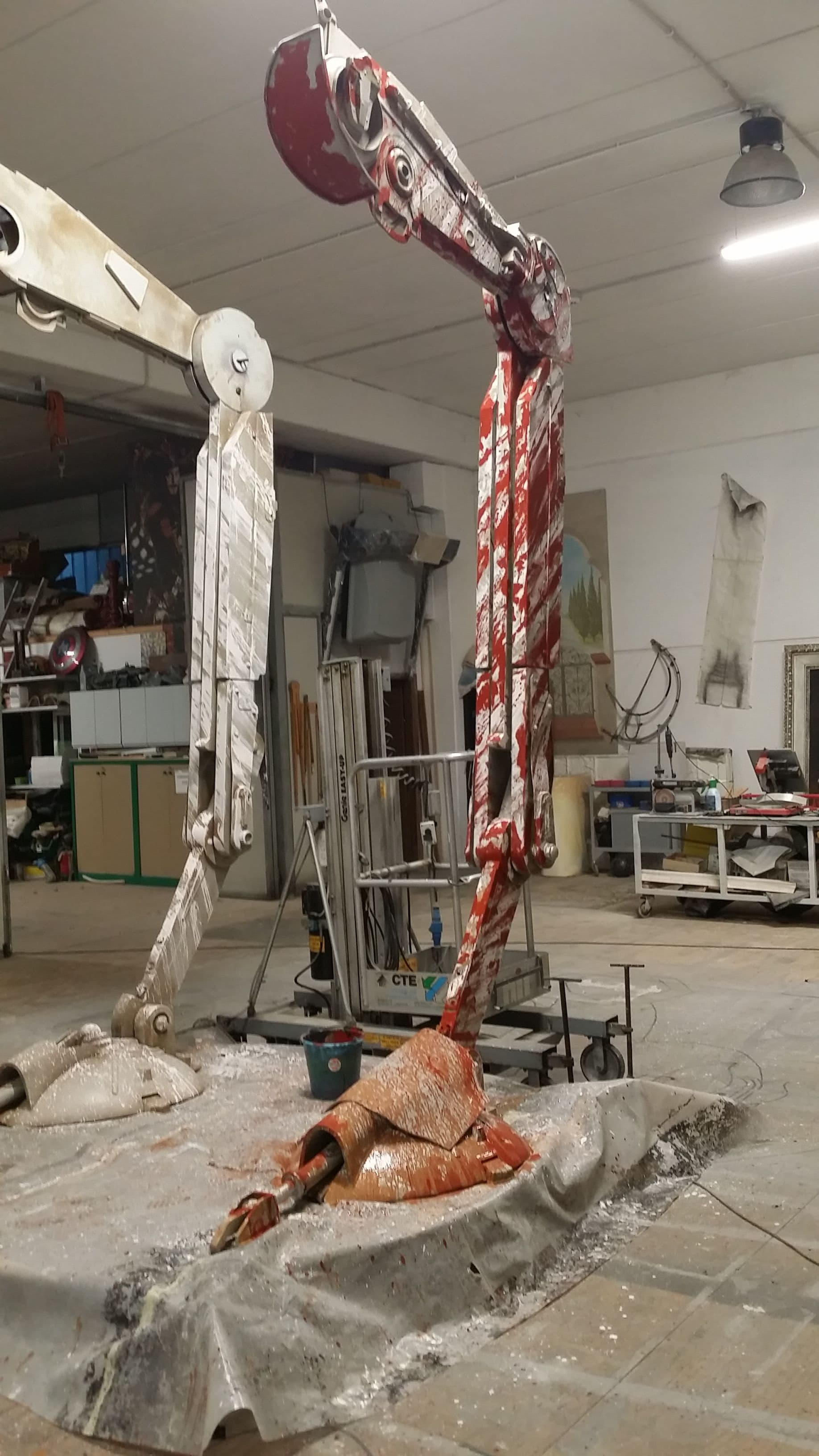 Particolare delle gambe del camminatore con una sezione dipinta di rosso e dettagli di finitura scenografica in laboratorio.