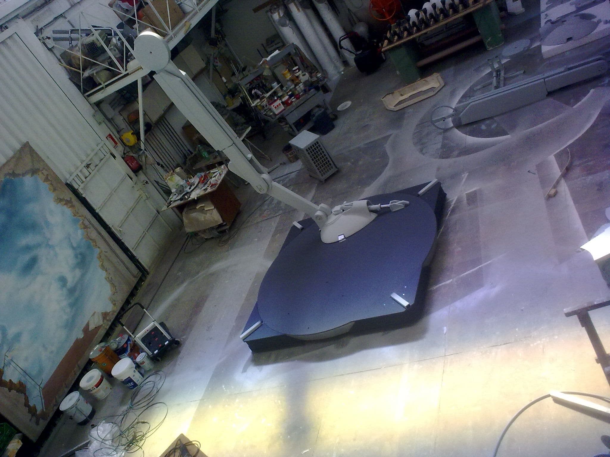 Vista dall'alto della prima gamba dell'AT-ST fissata alla piattaforma di supporto nell'officina scenografica.