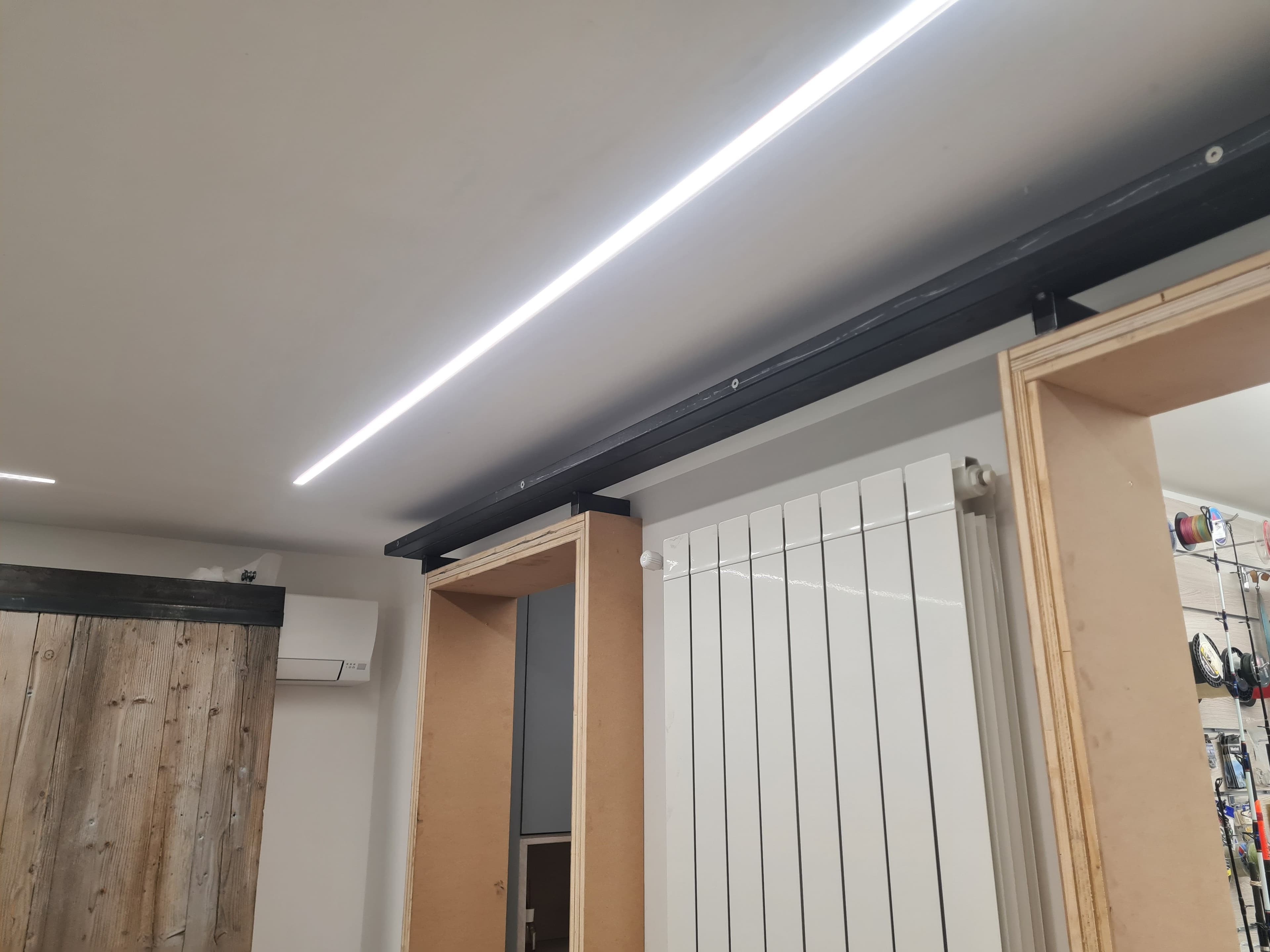 Dettaglio del binario superiore e dei telai in legno durante il montaggio a soffitto.